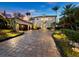 Elegant two-story home with a paver driveway and lush landscaping at 65 Lighthouse Point Dr, Longboat Key, FL 34228