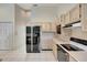 Kitchen with light wood cabinets, black appliances, and tile floors at 15903 Armistead Ln, Odessa, FL 33556