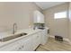 Bright laundry room with white cabinets, quartz countertops, and stainless steel sink at 901 30Th E Ct, Bradenton, FL 34208