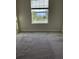 Bright bedroom with grey carpet and a large window overlooking a residential area at 16721 Barnwood Pl, Bradenton, FL 34211