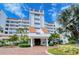 Stunning building featuring a striking white facade and elegant red tile roofs, surrounded by vibrant, lush tropical landscaping at 4545 Gulf Of Mexico Dr # 408, Longboat Key, FL 34228