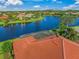 Property with red tile roof and a screened patio near the lake at 521 Luminary Blvd, Osprey, FL 34229