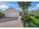 Tan house with white garage door, paved driveway, and lush landscaping at 5762 Benevento Dr, Sarasota, FL 34238