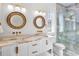 Bathroom with double vanity, large mirrors, and walk-in shower at 551 S Washington Dr, Sarasota, FL 34236