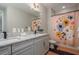 Double vanity bathroom with granite countertop and floral shower curtain at 5554 Sand Fossil Ct, Sarasota, FL 34238