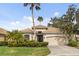 Tan one-story house with a two-car garage and lush landscaping at 9143 Willow Brook Dr, Sarasota, FL 34238
