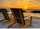 A picture perfect beach scene features two chairs on the sand, with a gorgeous sunset in the background at 1305 4Th St # 402P, Sarasota, FL 34236