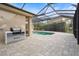 Outdoor kitchen with built-in grill, adjacent to a refreshing pool and screened enclosure at 7042 Twin Hills Ter, Lakewood Ranch, FL 34202