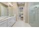 Bathroom with a double vanity, marble countertop, and walk-in shower with decorative tiling, next to a bedroom at 4611 Trento Pl, Bradenton, FL 34211