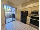 Kitchen features black appliances, tile floor, and access to patio at 5496 Hampstead Heath # 10, Sarasota, FL 34235