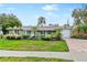 Green house with landscaped yard, brick driveway, and attached garage at 6623 Glades Way, Sarasota, FL 34231