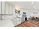 Charming kitchen with white cabinetry, stainless steel appliances, decorative shelving, and wood-style flooring at 151 Adair Ave, Sarasota, FL 34243