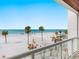 Stunning beachfront view from a spacious balcony with tropical palm trees and crystal blue water at 1035 Seaside Dr # 305, Sarasota, FL 34242