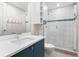 Modern bathroom features a blue vanity, white tiling, and a glass enclosed shower at 1035 Seaside Dr # 305, Sarasota, FL 34242