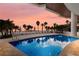 Resort pool with palm trees and lounge chairs overlooks the ocean at sunset at 1035 Seaside Dr # 305, Sarasota, FL 34242