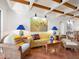 Living room with terracotta floors, yellow couch, and wood beam ceilings at 1080 W Peppertree Ln # 506A, Sarasota, FL 34242