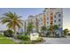 Beautiful condo building featuring a branded sign, palm trees, well-maintained landscaping, and colorful facade at 505 Tamiami N Trl # 201, Venice, FL 34285