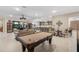 Expansive living room with a billiard table, seamless flow to dining area, and access to outdoor patio at 5050 Surfside Cir, Lakewood Ranch, FL 34211