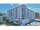 Modern high-rise condo building featuring balconies, palm trees and vibrant mural, under a blue sky at 111 S Pineapple Ave # 1018, Sarasota, FL 34236