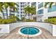 Inviting hot tub with a stainless-steel grab bar sits on a wood deck with palm trees and building in the background at 111 S Pineapple Ave # 1018, Sarasota, FL 34236