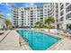 Beautiful pool with lounge chairs and tables and manicured landscaping in front of a modern condo building at 111 S Pineapple Ave # 1018, Sarasota, FL 34236