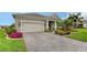Tan house with landscaped yard, paver driveway, and two-car garage at 13789 Old Creek Ct, Parrish, FL 34219
