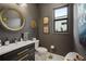 Dark-themed bathroom with modern vanity, round mirror, and gold accents at 17424 Cresswind Ter, Bradenton, FL 34211