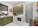 Modern laundry room with green cabinets and white appliances at 17424 Cresswind Ter, Bradenton, FL 34211