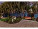 Landscaped backyard with lush tropical plants and a charming orange bench at night at 1923 Hibiscus St, Sarasota, FL 34239