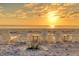 Scenic beach view at sunset with white chairs and small tables at 5965 Gulf Of Mexico Dr, Longboat Key, FL 34228