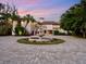 Elegant waterfront home with circular driveway and fountain at dusk at 749 Freeling Dr, Sarasota, FL 34242