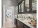Butlery with glass-front cabinets, marble countertops, and wine storage at 85 Sugar Mill Dr, Osprey, FL 34229