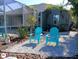 Relaxing backyard oasis with two turquoise chairs and a screened pool area at 10555 Old Grove Cir, Bradenton, FL 34212