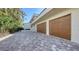 Three-car garage with paver driveway and wood-like garage doors at 50 Lighthouse Point Dr, Longboat Key, FL 34228