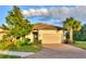 Tan house with tile roof, two-car garage, and landscaped yard at 5617 Piccolo St, Nokomis, FL 34275