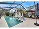 Inviting pool area with screened enclosure, lush landscaping, and patio furniture at 6609 Waterford Ln, Sarasota, FL 34238