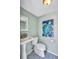 Quaint half bathroom with pedestal sink, toilet, and beach-themed art at 6609 Waterford Ln, Sarasota, FL 34238