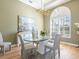 Elegant dining room with a glass table, light-colored chairs, and an arched window at 7123 Beechmont Ter, Lakewood Ranch, FL 34202