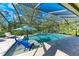 A screened-in pool area featuring a lounge chair, umbrella, and blue patio chairs in the pool's shallows at 13534 5Th Ne Ave, Bradenton, FL 34212