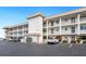 Condo building exterior showcasing light-colored facade and parking at 3330 Gulf Of Mexico Dr # 205D, Longboat Key, FL 34228