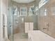 Modern bathroom with a glass shower, soaking tub and grey tile at 609 Colonial Bay Dr, Nokomis, FL 34275