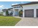 Two-story home with light-colored siding, a three-car garage, and a landscaped yard at 609 Colonial Bay Dr, Nokomis, FL 34275