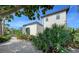 White stucco house with a tile roof, lush landscaping, and a two-car garage at 2402 Palmetto St, Nokomis, FL 34275
