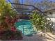 Inviting pool area with screened enclosure, lush landscaping, and patio furniture at 8224 Country Oaks Ct, Sarasota, FL 34243