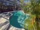 Inviting pool area with screened enclosure, lush landscaping, and patio furniture at 8224 Country Oaks Ct, Sarasota, FL 34243