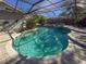Inviting pool area with screened enclosure, lush landscaping, and patio furniture at 8224 Country Oaks Ct, Sarasota, FL 34243
