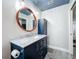 Bathroom with a marble countertop, dark blue vanity, and a large round mirror at 161 Sandhurst Dr, Venice, FL 34293