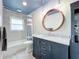 Updated bathroom with a marble countertop, dark blue vanity, and a large mirror at 161 Sandhurst Dr, Venice, FL 34293