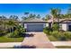 One-story house with gray garage door and a brick driveway, surrounded by landscaping and other homes at 2479 Brassica Dr, North Port, FL 34289