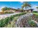 Community center featuring lush landscaping, stone accents, and a covered entrance for residents at 7115 Callander Cv, Lakewood Ranch, FL 34202
